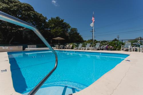 a swimming pool with blue water and white chairs at A Beach Breeze Inn in West Harwich