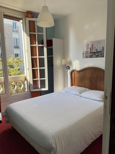 a bedroom with a white bed and a window at Hôtel Verlaine in Paris