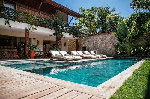 a swimming pool with lounge chairs next to a house at VillaMag in Jericoacoara