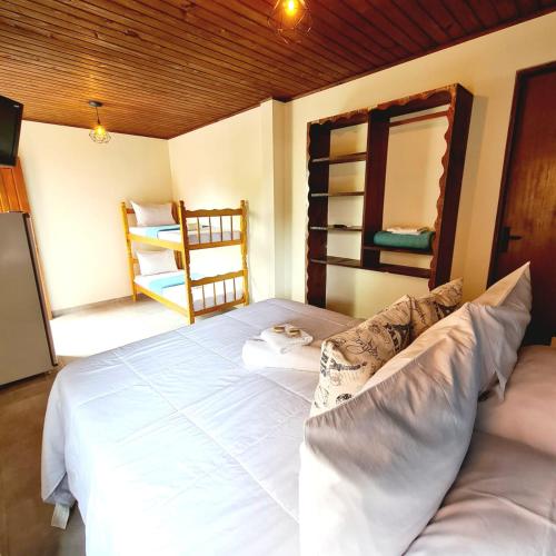 a bedroom with a large white bed with a mirror at Pousada Doce Mar in Guarda do Embaú