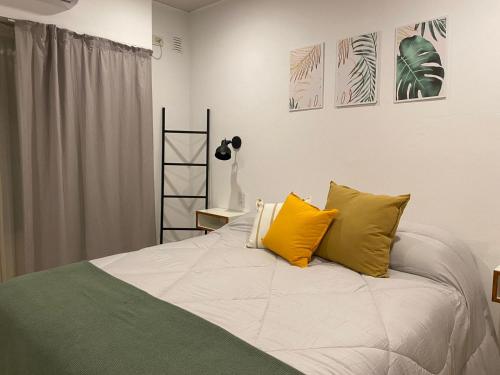 a bedroom with a bed with two yellow pillows at Studio Estrada 2 Escobar in Belén de Escobar