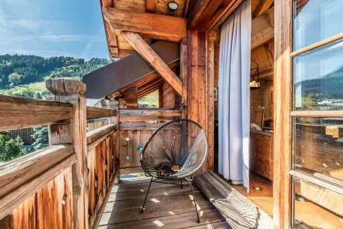 - un fauteuil à bascule sur la terrasse couverte d'une cabane en rondins dans l'établissement Apartment Garapa Morzine - by EMERALD STAY, à Morzine