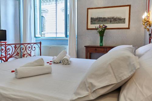 ein weißes Bett mit zwei Kissen und einer Vase mit Blumen in der Unterkunft 8cento al Valentino in Turin