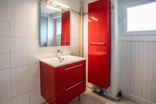 La salle de bains rouge est pourvue d'un lavabo et d'un miroir. dans l'établissement L'ÉCLUSE TERRASSE PARKING GRATUIT Home-One, à Dole