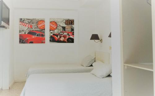 una camera da letto bianca con due poster sul muro di Hostal On Dormire Valencia a Valencia