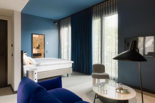 a bedroom with blue walls and a blue couch and a bed at EmiLu Design Hotel in Stuttgart