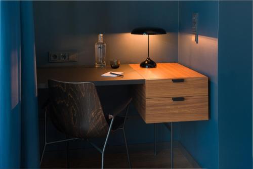 a desk with a lamp and a chair in a room at EmiLu Design Hotel in Stuttgart