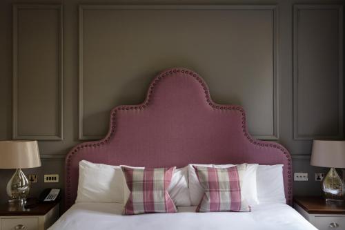 a bed with a pink headboard and white pillows at Murrayshall Country Estate in Perth
