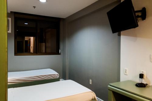 a small room with two beds and a mirror at Master Express Alberto Bins - 200 metros do Hospital Santa Casa in Porto Alegre