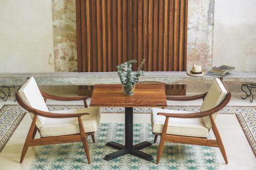 a table with two chairs and a vase with a plant on it at TreeHouse Boutique Hotel, an adults only boutique hotel in Mérida