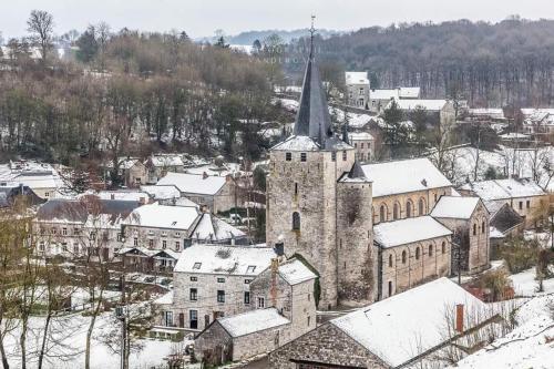 an old building with a steeple in a town covered in snow at Lesse en Ciel vous accueille avec plaisir . in Houyet