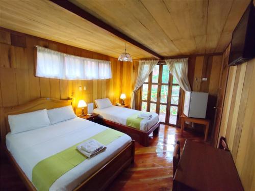 a bedroom with two beds and a television in it at Hotel El Auca in Puerto Francisco de Orellana