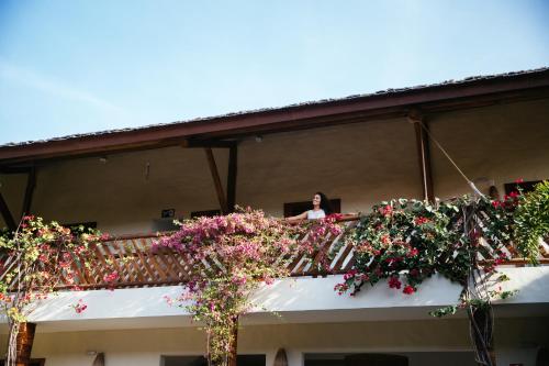 a woman standing on the balcony of a building with flowers at VillaMag in Jericoacoara