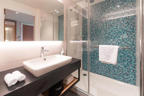 a bathroom with a sink and a glass shower at Holiday Inn Paris CDG Airport an IHG Hotel in Roissy-en-France