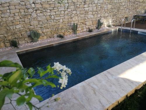 - une piscine en face d'un mur en pierre dans l'établissement La Closerie du Château, à Uzès
