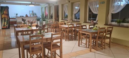 un restaurante con mesas y sillas de madera y ventanas en NOCLEGI Niemodlin en Niemodlin