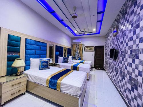2 łóżka w pokoju hotelowym z niebieskim oświetleniem w obiekcie Horizon Hotel w mieście Lahaur
