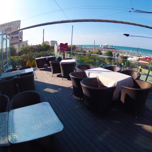 a balcony with tables and chairs and a view of the ocean at City Hotel in Senigallia