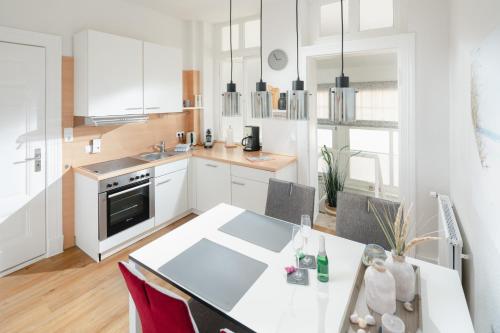 a kitchen with white cabinets and a table with chairs at Fewo Grete in Norderney