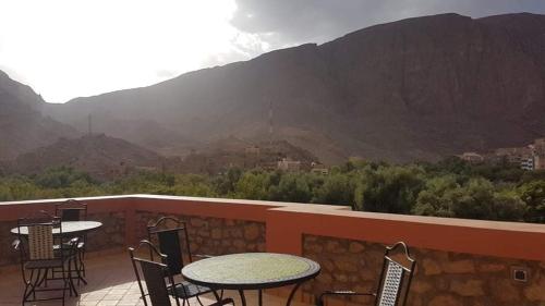 a patio with tables and chairs and a view of a mountain at Auberge Restaurant Fatihi Freres in Tinerhir