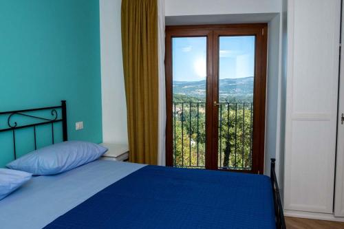 a bedroom with a blue bed and a large window at IL MASCHERONE in Sepino