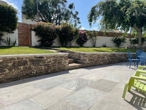 a patio with chairs and a retaining wall at Sunny Corner, Padstow. Spacious 3 bedrooms, 2.5 bathrooms, parking, garden. in Padstow