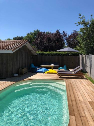 - une piscine dans un jardin avec une terrasse en bois dans l'établissement Maison Kyma, à Gujan-Mestras