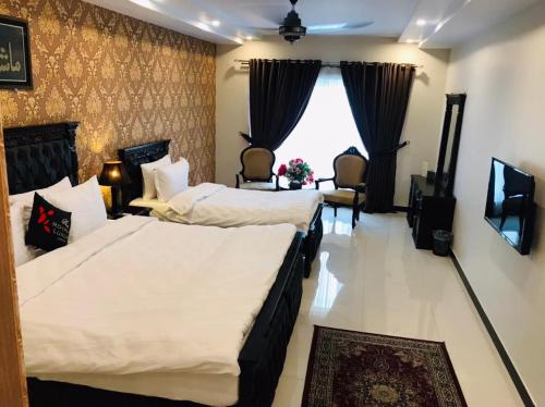 a hotel room with two beds and a window at Royaute Luxury Hotel Sialkot in Sialkot