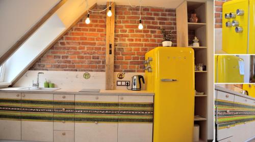 a yellow refrigerator in a kitchen with a brick wall at Jono Apartment in Klaipėda