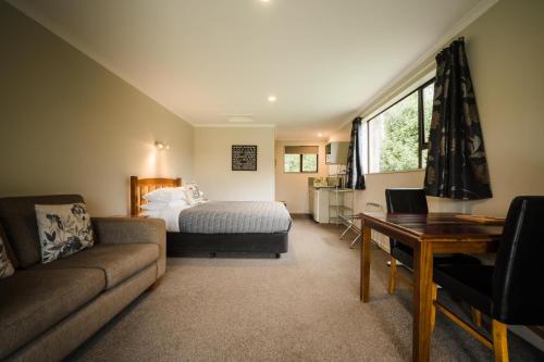 Invercargill Holiday Park & Motels في إنفيركارجِِيل: غرفة نوم بسرير واريكة وطاولة
