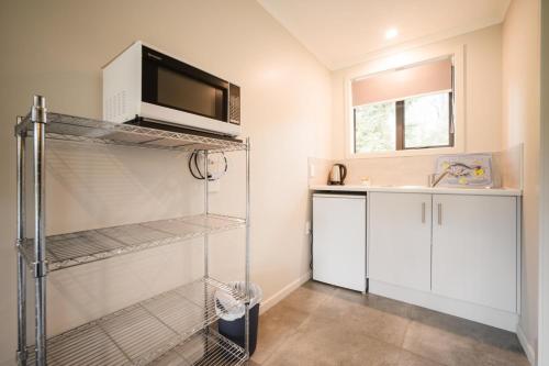 uma cozinha com um micro-ondas e um lavatório em Invercargill Holiday Park & Motels em Invercargill