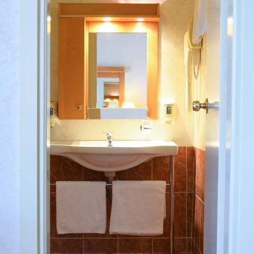 a bathroom with a sink and a mirror and towels at Seaside Hotel in Loutraki