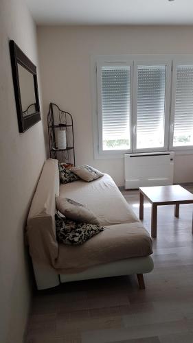 1 dormitorio con cama, mesa y ventanas en appartement entre Mer et Corbières, en Cuxac-dʼAude