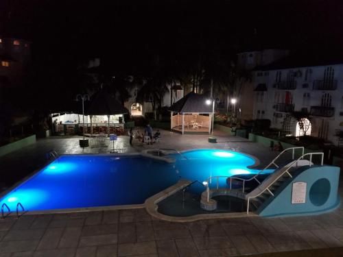 a swimming pool at night with a slide in it at WINS On The Beach (@ Sandcastles Resort) in Ocho Rios
