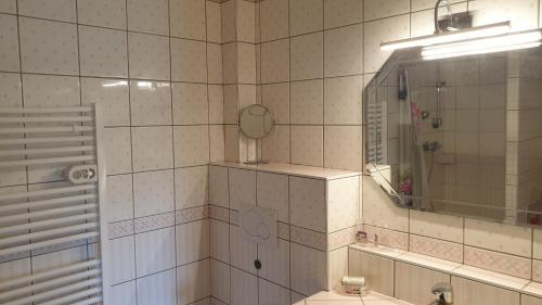 La salle de bains est pourvue de carrelage blanc, d'un lavabo et d'un miroir. dans l'établissement Le Grossglockner, aux Contamines-Montjoie