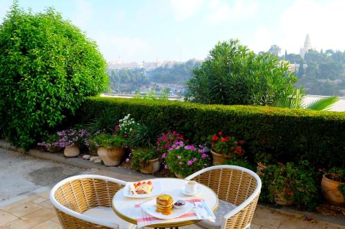 einen Tisch und Stühle auf einer Terrasse mit Blumen in der Unterkunft St Andrews Guest House in Jerusalem