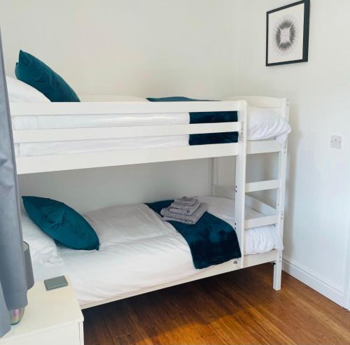 two bunk beds in a room with a desk at Sunny Corner, Padstow. Spacious 3 bedrooms, 2.5 bathrooms, parking, garden. in Padstow