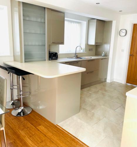 a white kitchen with a sink and a counter at Sunny Corner, Padstow. Spacious 3 bedrooms, 2.5 bathrooms, parking, garden. in Padstow