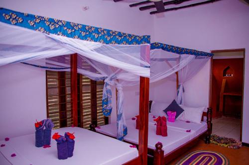 a bedroom with two beds with presents under a canopy at Zanzi Rest Bungalow in Nungwi