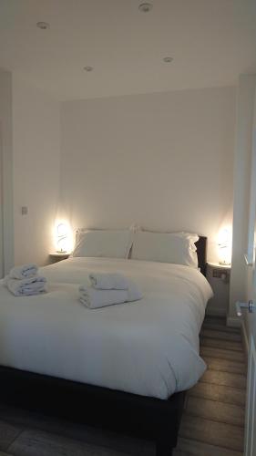 a white bed with two towels on top of it at BexLet in Bexhill