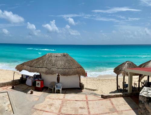 a beach with some chairs and umbrellas and the ocean at Preciosos Estudio Vista al Mar o jardín in Cancún