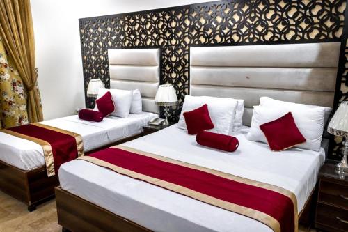 two beds in a hotel room with red pillows at Rose Palace Hotel, Gulberg in Lahore