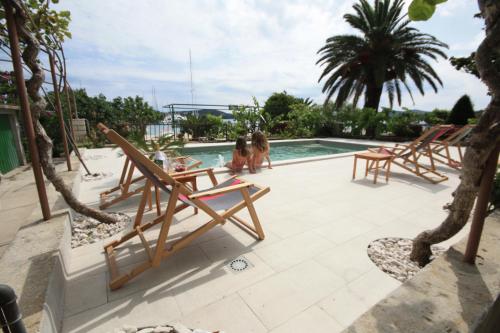 a group of chairs sitting next to a swimming pool at Apartments Gina in Trogir