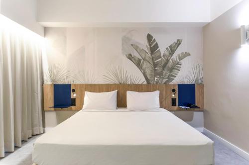 a bedroom with a large bed with white sheets at Novotel Salvador Rio Vermelho in Salvador