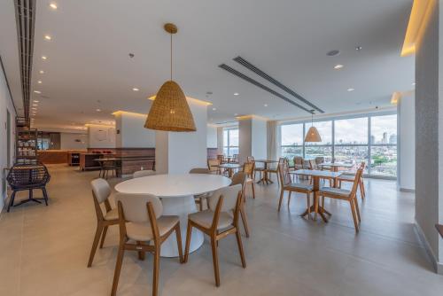 a dining room with tables and chairs and windows at Novotel Salvador Rio Vermelho in Salvador