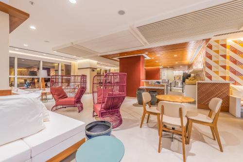 a living room with a white couch and chairs at Novotel Salvador Rio Vermelho in Salvador