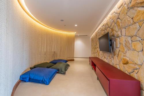 a bedroom with two beds and a stone wall at Novotel Salvador Rio Vermelho in Salvador