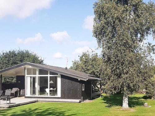 een zwart huis met een patio en een boom bij 5 person holiday home in Odder in Odder