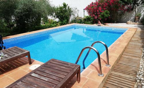 - une piscine avec 2 chaises et un banc dans l'établissement El alojamiento rural de Peter, à Corterrangel