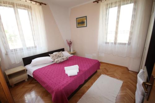 a bedroom with a pink bed with two windows at Apartments Gina in Trogir